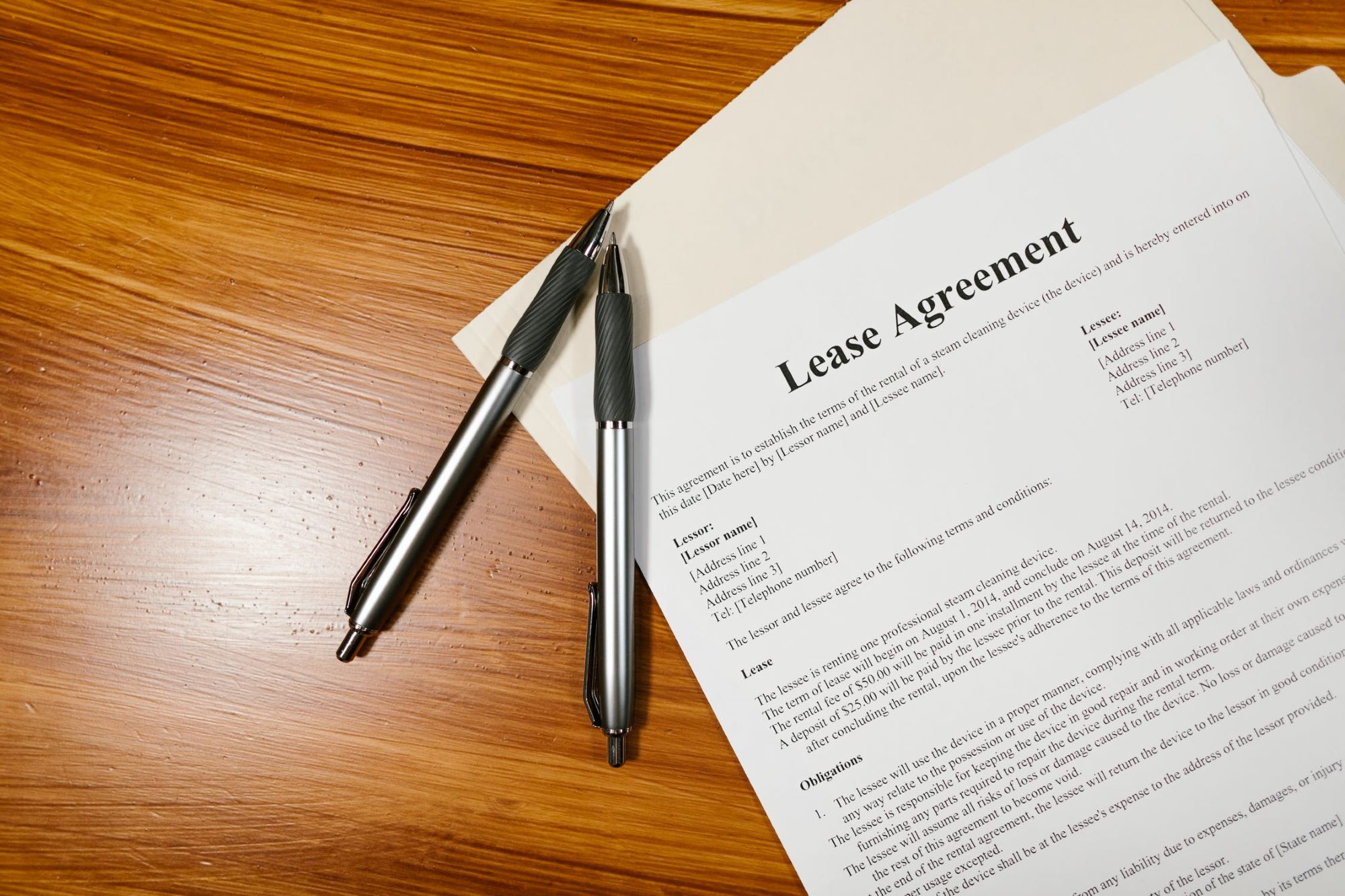 A lease agreement on a wooden table with two pens next to it
