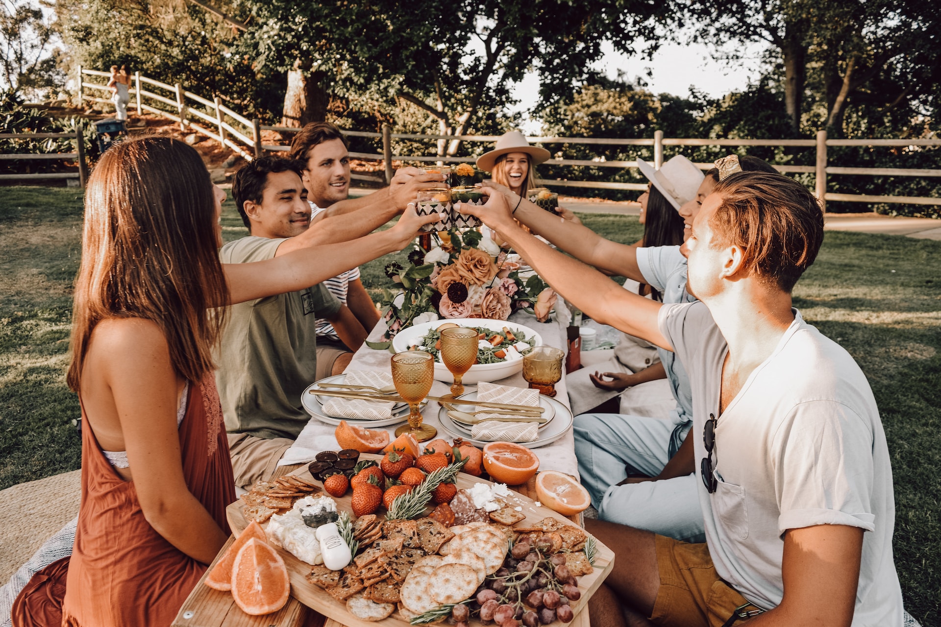 Group of people having a toast around a table with a spread of food.